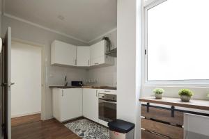 uma pequena cozinha com armários brancos e uma janela em Low Cost Apartments Center Elche em Elche