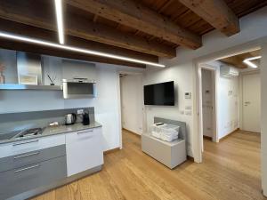 a kitchen with white cabinets and a flat screen tv at Residenza Della Samaritana in Verona