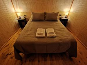 1 dormitorio con 1 cama con 2 toallas en Cabañas Ancestral, en Hornopirén