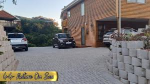 een huis met twee auto's geparkeerd voor een oprit bij 44 Nature On Sea in Groot Brak Rivier