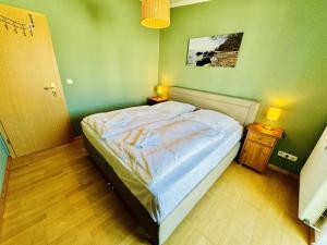 uma cama num quarto com uma parede verde em Haus Juliane, Seesand em Warnemünde