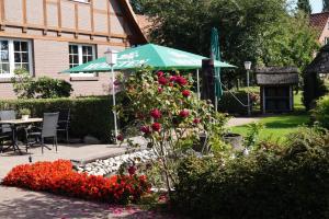 un jardín con una sombrilla verde y algunas flores en Gasthof Isernhagen, en Gödenstorf