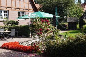 einen Garten mit einem grünen Sonnenschirm und ein paar Blumen in der Unterkunft Gasthof Isernhagen in Gödenstorf