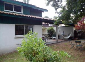 une maison avec une terrasse et un hamac dans la cour dans l'établissement Village de l'herbe réf 2094, à Lège-Cap-Ferret