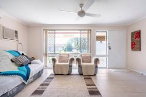 a bedroom with two chairs and a bed and a fan at Sydney Blue Mountain Retreat in Kingswood