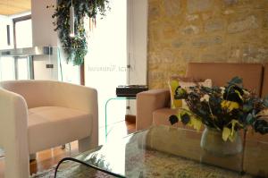 Hotel Baeza Monumental by eme hoteles في بايزا: غرفة معيشة مع كراسي وطاولة مع إناء من الزهور
