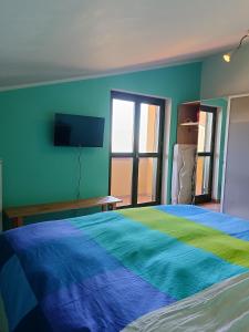 1 dormitorio con 1 cama y TV en la pared en Soggiorno con splendida vista, en Monforte dʼAlba