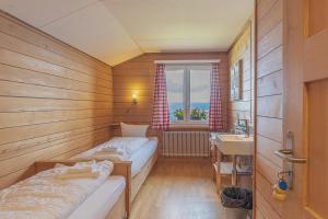 Cette petite chambre comprend 2 lits et un lavabo. dans l'établissement Berghaus Niederhorn, à Beatenberg