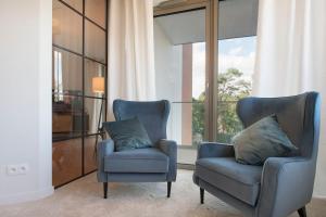 two blue chairs in a room with a window at Apartament Premium PINEA 323 in Pobierowo