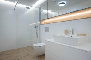 a white bathroom with a toilet and a sink at Apartament Premium PINEA 323 in Pobierowo