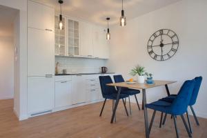 uma cozinha com mesa e cadeiras e um relógio em Apartament Premium PINEA 323 em Pobierowo