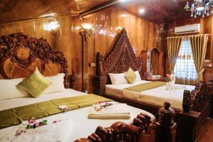 two beds in a room with wooden walls at Srey Krob Leak Resort in Battambang