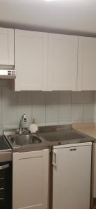 una cucina con lavandino e armadietti bianchi di Gli scogli a due passi a Portovenere