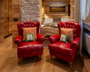 Duas cadeiras vermelhas e uma cama num quarto em Asiago Sporting Hotel & Spa em Asiago