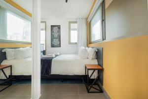 a bedroom with a white bed and two windows at BHomy Melo in Sao Paulo