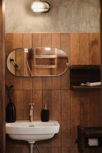 La salle de bains est pourvue d'un lavabo et d'un miroir mural. dans l'établissement Cabin Home อยู่ป่า wild and free, à Ko Larn