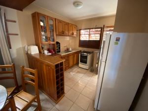 - une cuisine avec des placards en bois et un réfrigérateur blanc dans l'établissement Casa em condomínio fechado Amaralina, à Porto Seguro