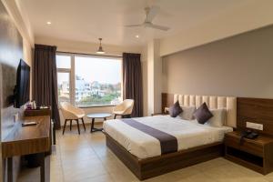 um quarto de hotel com uma cama, uma secretária e uma janela em The Living Hub Business Hotel, Kolhapur em Kolhapur