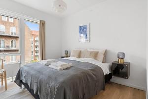 Un dormitorio blanco con una cama grande y una ventana en A stylish getaway in modern surroundings, en Aarhus