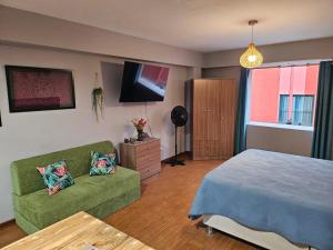 een slaapkamer met een bed, een bank en een tv bij Espaciosos y lindos mini apartamentos in Lima