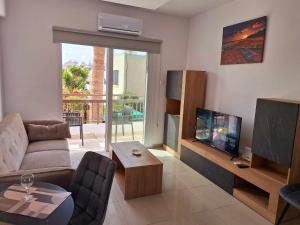 ein Wohnzimmer mit einem Sofa und einem Flachbild-TV in der Unterkunft Stylish Apt Kato Paphos Close to Beach & Vibrant Harbor Life in Paphos City