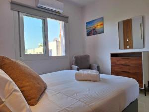 a bedroom with a bed and a chair and a window at Stylish Apt Kato Paphos Close to Beach & Vibrant Harbor Life in Paphos