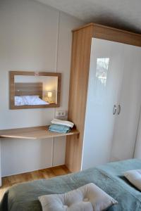 a bedroom with a bed and a mirror at Chalet 27 in Zandvoort