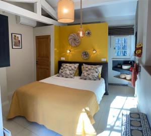 - une chambre dotée d'un lit avec un mur jaune dans l'établissement La Vagabonde, à Saint-Tropez