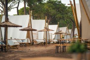 eine Gruppe von Tischen und Stühlen mit Sonnenschirmen in der Unterkunft Kampaoh Costa Brava in Pals