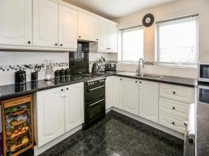 una cocina con armarios blancos y electrodomésticos negros en Diamond house, en Darlaston