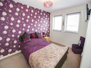 Diamond house في Darlaston: غرفة نوم مع سرير أرجواني مع جدار نمط زهرة