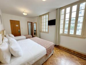 Schlafzimmer mit einem großen weißen Bett und Fenstern in der Unterkunft Hotel Monte Alegre in Rio de Janeiro