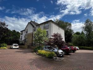 a building with cars parked in a parking lot at Riverside one bedroom flat in Bridge of Allan