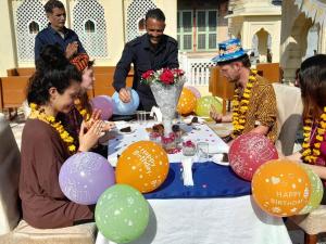 a group of people sitting around a table with balloons at Hotel Khandaka mahal in Jaipur