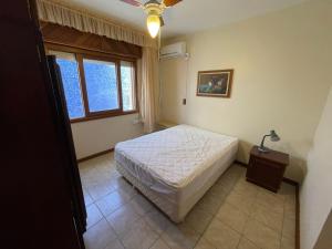 ein Schlafzimmer mit einem weißen Bett und einem Fenster in der Unterkunft Apartamento a uma quadra da praia in Capão da Canoa