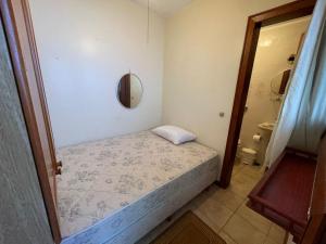 ein kleines Schlafzimmer mit einem Bett und einem Spiegel in der Unterkunft Apartamento a uma quadra da praia in Capão da Canoa + 1 Foto
