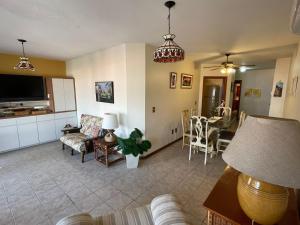 ein Wohnzimmer mit einer Couch, einem Fernseher und einem Tisch in der Unterkunft Apartamento a uma quadra da praia in Capão da Canoa