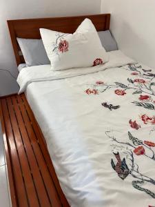 a bed with a white comforter with flowers on it at Reinhardshausen Suites and Residences- Lovely Air-Conditioned Units in Tuguegarao City