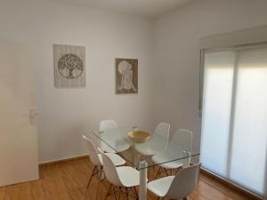 a dining room with a glass table and white chairs at Exclusivo Apartamento ALZIRA in Alzira