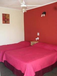 a red bedroom with two beds with pink sheets at Hostel & Posada Noelia in Puerto Iguazú