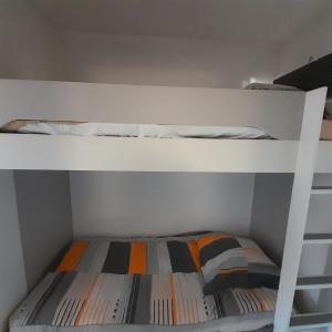 białe łóżko piętrowe z pomarańczową i szarą poduszką w obiekcie Cosy Studio 3mn de la mer Clim Parking Wifi w mieście Sanary-sur-Mer