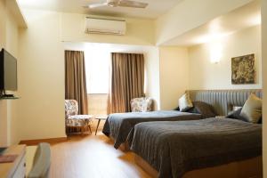 ein Hotelzimmer mit 2 Betten und einem TV in der Unterkunft Hotel Diplomat, Colaba in Mumbai
