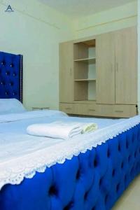 a bed with a blue headboard and a wooden cabinet at Arctic kerugoya in Keruguya