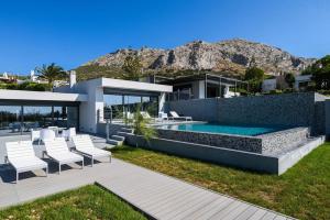 una casa con piscina e sedie bianche di Luxury Beachfront Villa Selenia Gold in Sounio a Sounio