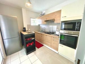 uma cozinha com armários de madeira e um frigorífico de aço inoxidável em Appartement de la Mer et du Levant em Schœlcher