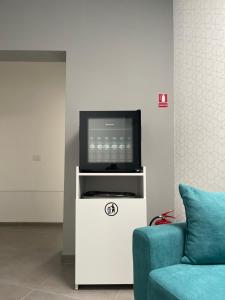 a television on a white entertainment center with a blue couch at Rooms in Bacău +50 photos