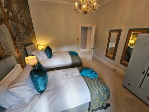 1 dormitorio con 2 camas y lámpara de araña en Merchant's View - Luxury Seaside Designer Retreat, en Rothesay