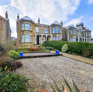 a large house with a gravel yard in front of it at Merchant's View - Luxury Seaside Designer Retreat in Rothesay