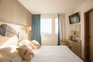 sypialnia z białym łóżkiem i oknem w obiekcie Hotel Port Marine w mieście Sète