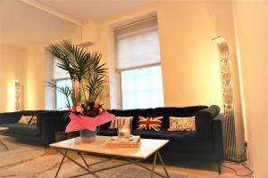 ein Wohnzimmer mit einem schwarzen Sofa und einem Tisch in der Unterkunft Cozy place Soho London in London